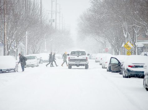 Pedestrians cross the street during a snow storm in Winona Tuesday, Feb. 2. Pedestrian Safety has been a major topic of discussion since Winona State University student Britney Nelson was hit by a driver in early November. (Photo by Jacob Striker) 