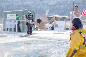 St. Mary student Musau Alfaghan belly flops into the ice-cold water at the Goose Bump Jump Saturday, Feb. 13. (Photo by Taylor Nyman)