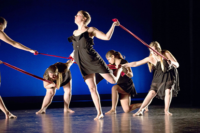 Dancer Sydney Swanson (middle) holds a red cloth in the dance “Unreliable Narrator,” which represents the connection of individuals in our society even when everyone’s outer appearance is different.
