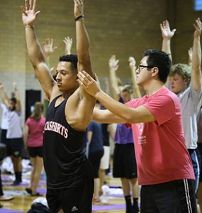 Dan Lee (right) helps first-year defensive back Christopher Schroeder position his body for a stretch during the RoFlow program in Talbot Gymnasium with Winona State’s football team on Thursday. Lee is part of the Recovery and Movement Enhancement (FRAME) club. (Photo by Kendahl Schlueter)