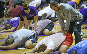 HERS professor Justin Geijer (right) and HERS students help Warrior football players stretch during RoFlow, as part of the FRAME club. These exercises take place every Sunday and Thursday night. (Photo by Kendahl Schlueter)