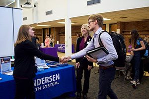 Senior Zach Spanton shakes hands with Karen Torud and Jen Schulz at the Gundersen Health System table at the Career Expo in East Hall Thursday, Sept. 29. He currently works at an agency in La Crosse, Wis. but decided to attend the Career Expoto work on his face-to-face communication with employers. (Photo by Brianna Murphy)