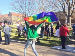 A student raises the pride flag at Winona State’s sit-in on Monday, Nov. 21. The sit-in was organized as a constructive response to the current  political climate in the U.S.  (Photo by Colin Kohrs)