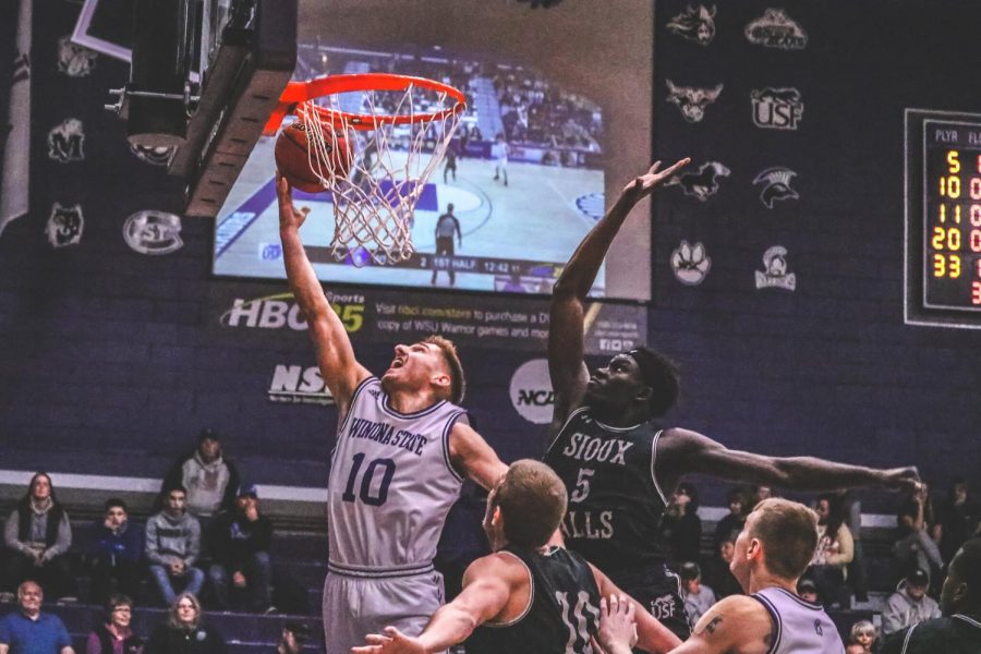 Winona State guard Caleb Wagner, dunks despite the efforts of University of Sioux Falls forward Teathloach Pal, a senior during a game at Winona State’s McCown Gymnasium on Friday, Feb. 14. Winona State fell 49-51 in a tight game against Sioux Falls.