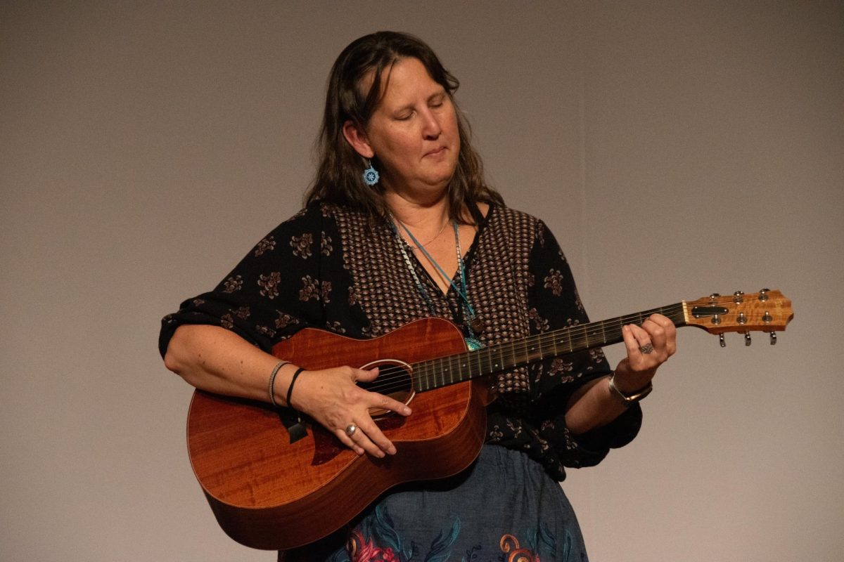 Lyz Jaakola holding her guitar at the DuFresne Performing Arts Center. She wrote her own song on guitar and sang it. She teaches music education and American Indian Studies at a community college. 