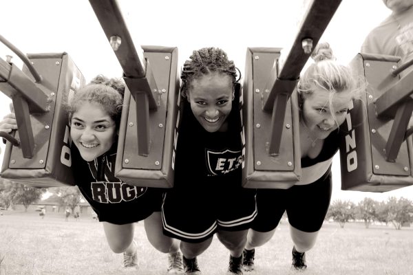 Using strength from their legs and core, three WSU Black Katts women rugby players push a scrum sled during practice.