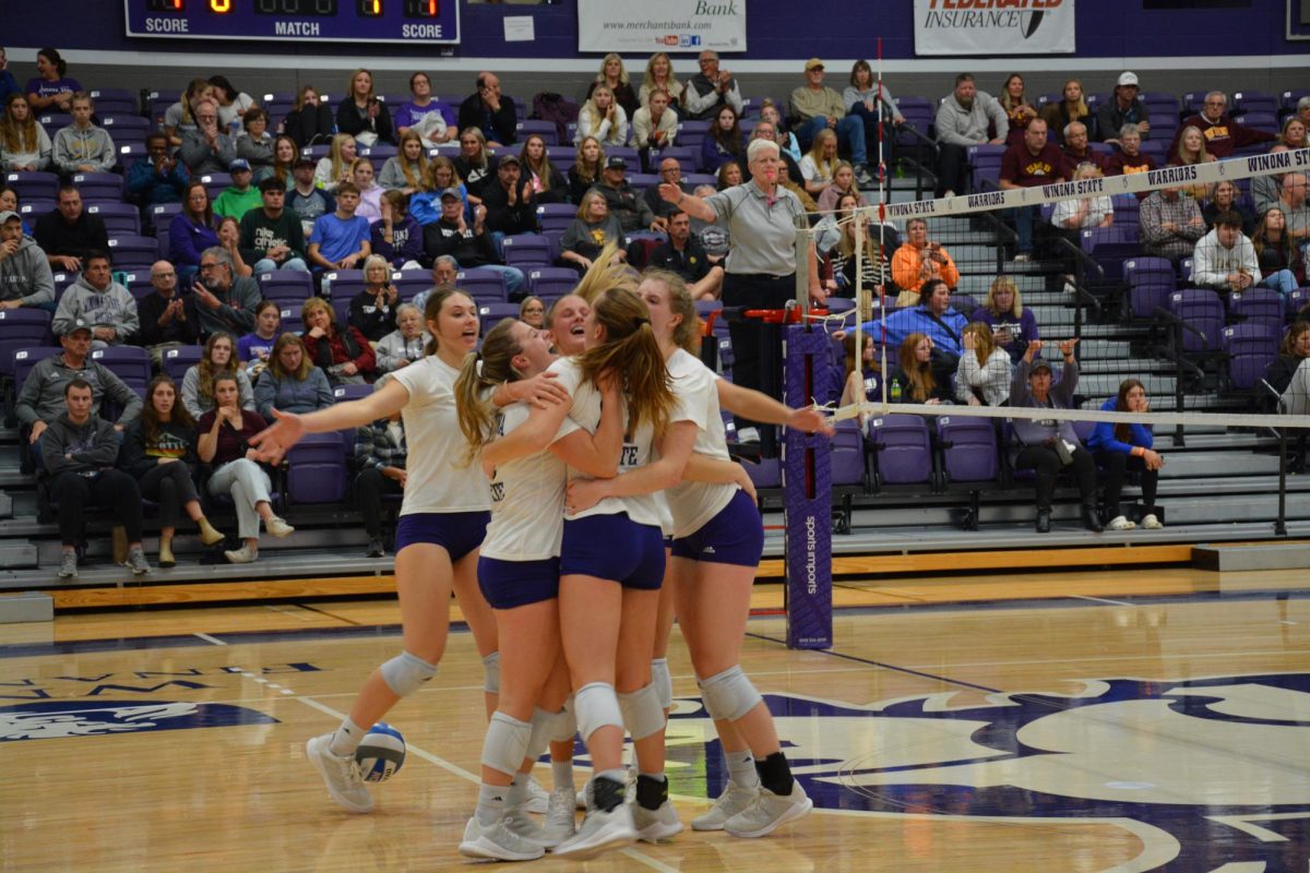 Women’s Volleyball team coming together in celebration after scoring a point against Minnesota Duluth.
