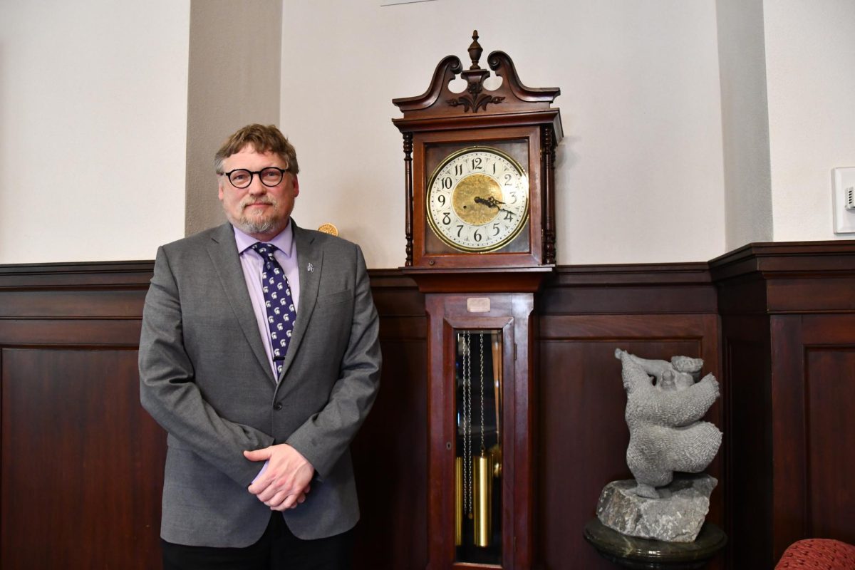Kenneth Janz stands in front of a hundred year old clock gift in the President’s office.