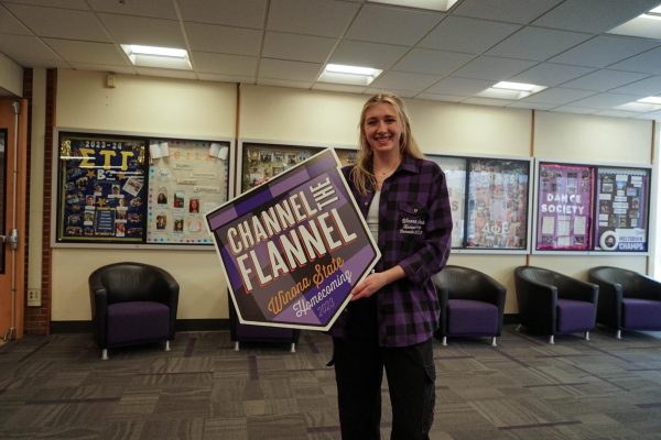 Third-year art and design student, Stephanie Dasbach, smiling brightly holding her design of Winona States’s Homecoming theme: Channel The Flannel.